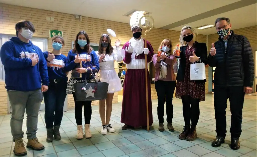 Gruppe mit Masken in der Schule, in der Mitte eine als Nikolaus verkleidete Person