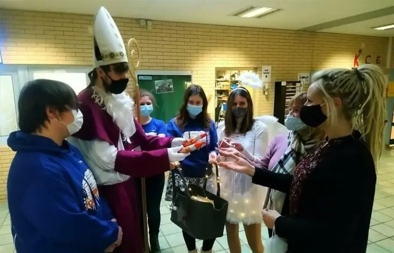 Schülerinnen und Schüler mit Masken übergeben Waren an eine als Nikolaus verkleidete Person