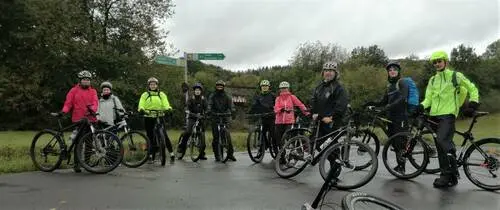 Gruppe Radfahrender mit Fahrrädern auf einem Feldweg unter grauem Himmel