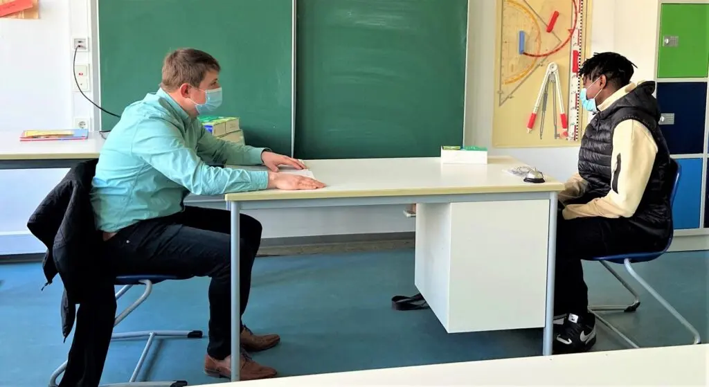 Bewerbungsgespräch-Simulation: Schüler sitzt einem Gesprächspartner an einem Tisch gegenüber