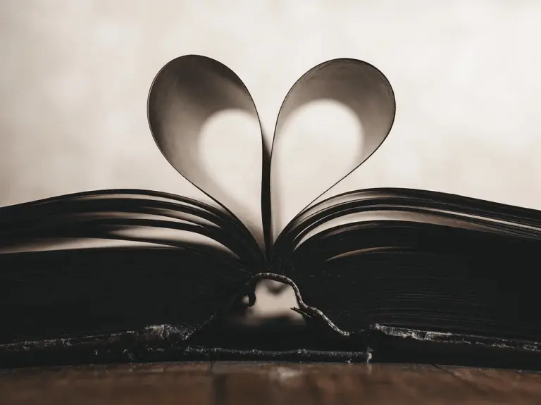Aufgeschlagenes Buch, dessen zwei Seiten zu einem Herz gebogen sind, in Schwarz-Weiß
