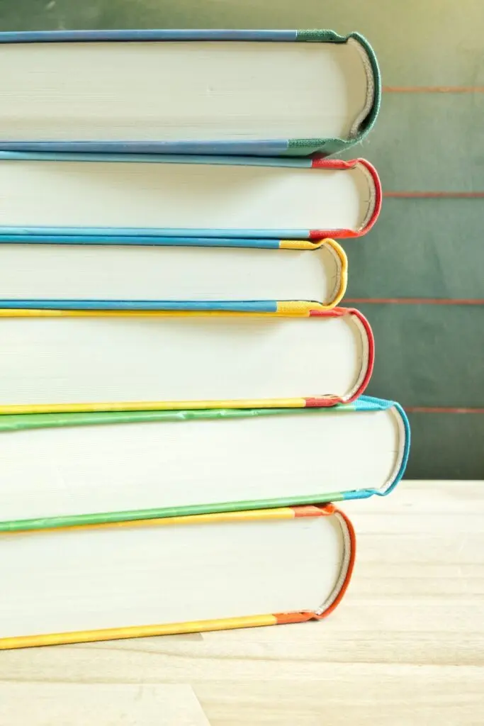 Stapel aus mehreren Büchern mit bunten Buchrücken, schräg übereinander gelegt, vor hellem Hintergrund
