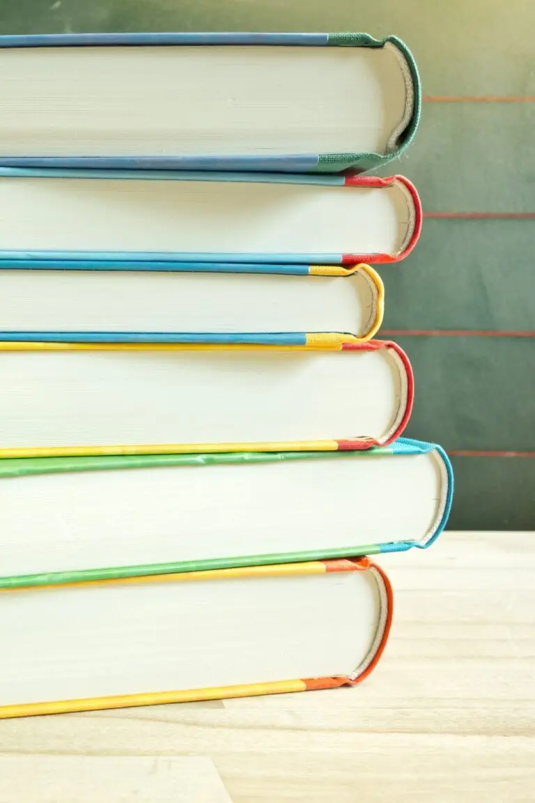 Stapel aus mehreren Büchern mit bunten Buchrücken, schräg übereinander gelegt, vor hellem Hintergrund