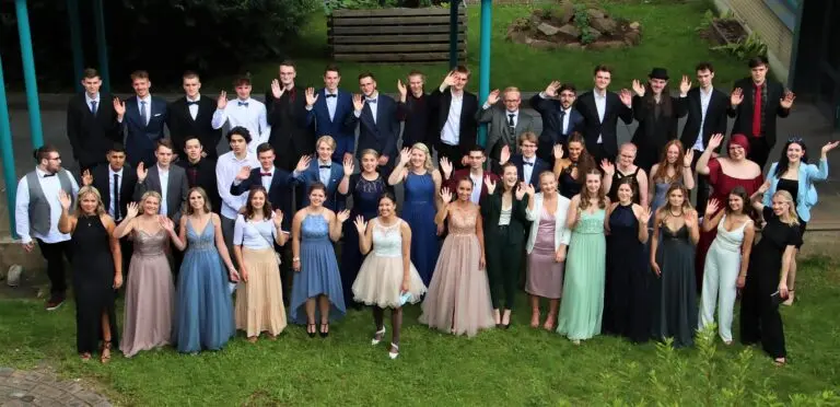 Gruppenfoto der Abiturientinnen und Abiturienten in festlicher Kleidung auf einer Wiese