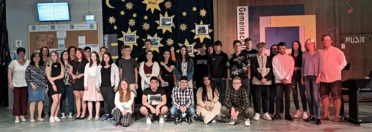 Großes Gruppenfoto der Absolventinnen und Absolventen in der Aula