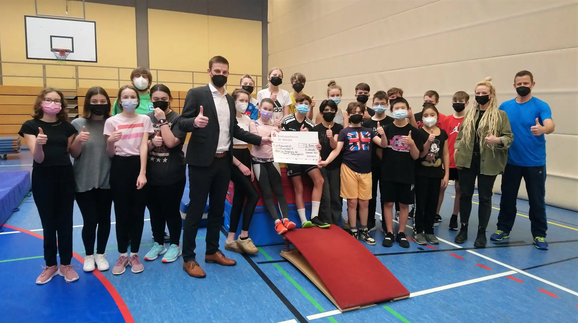 Klasse und Erwachsene in der Turnhalle mit Urkunde und neuen Turnmatten