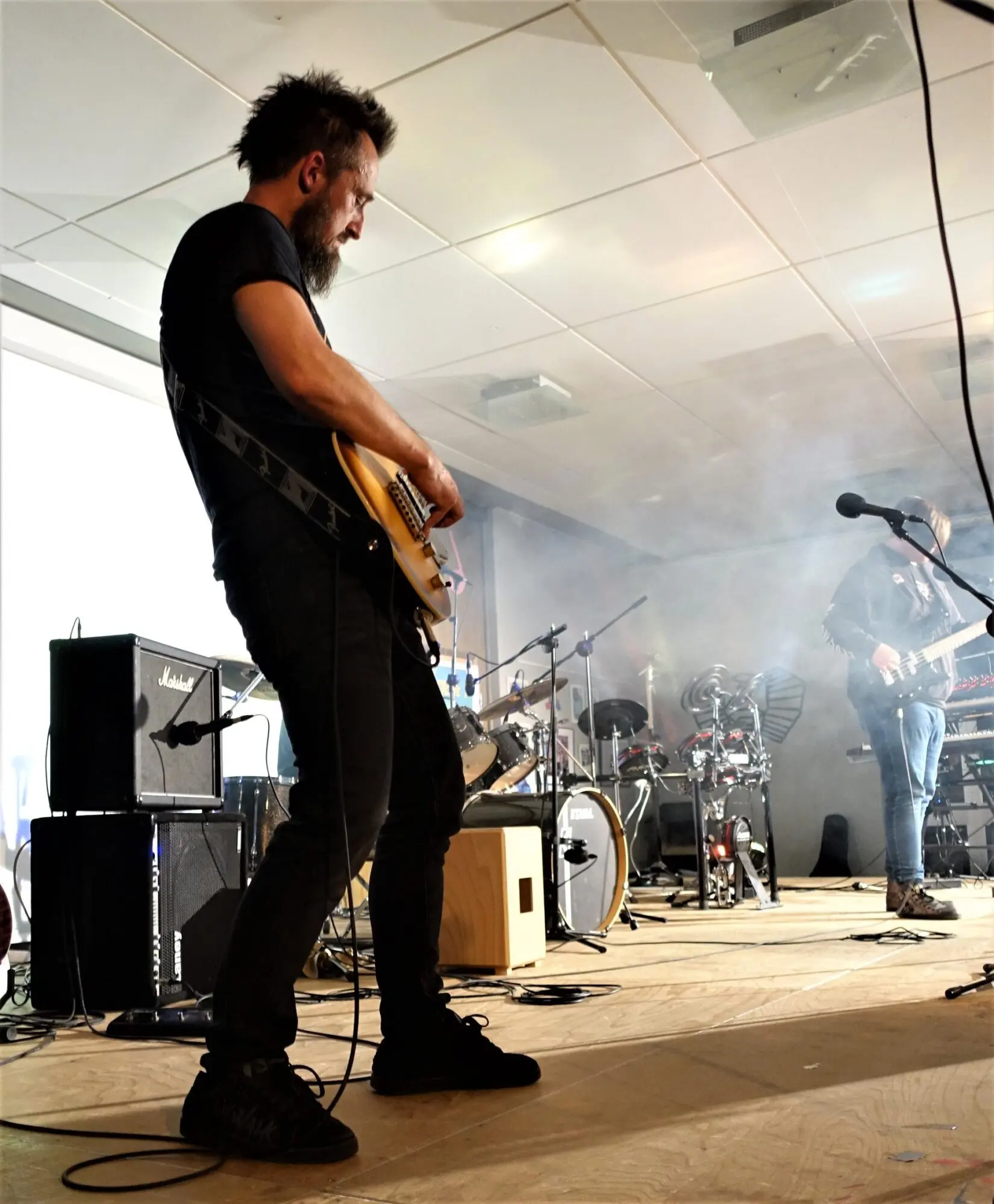 Gitarrist spielt E-Gitarre auf einer Bühne mit Nebel und Verstärkern