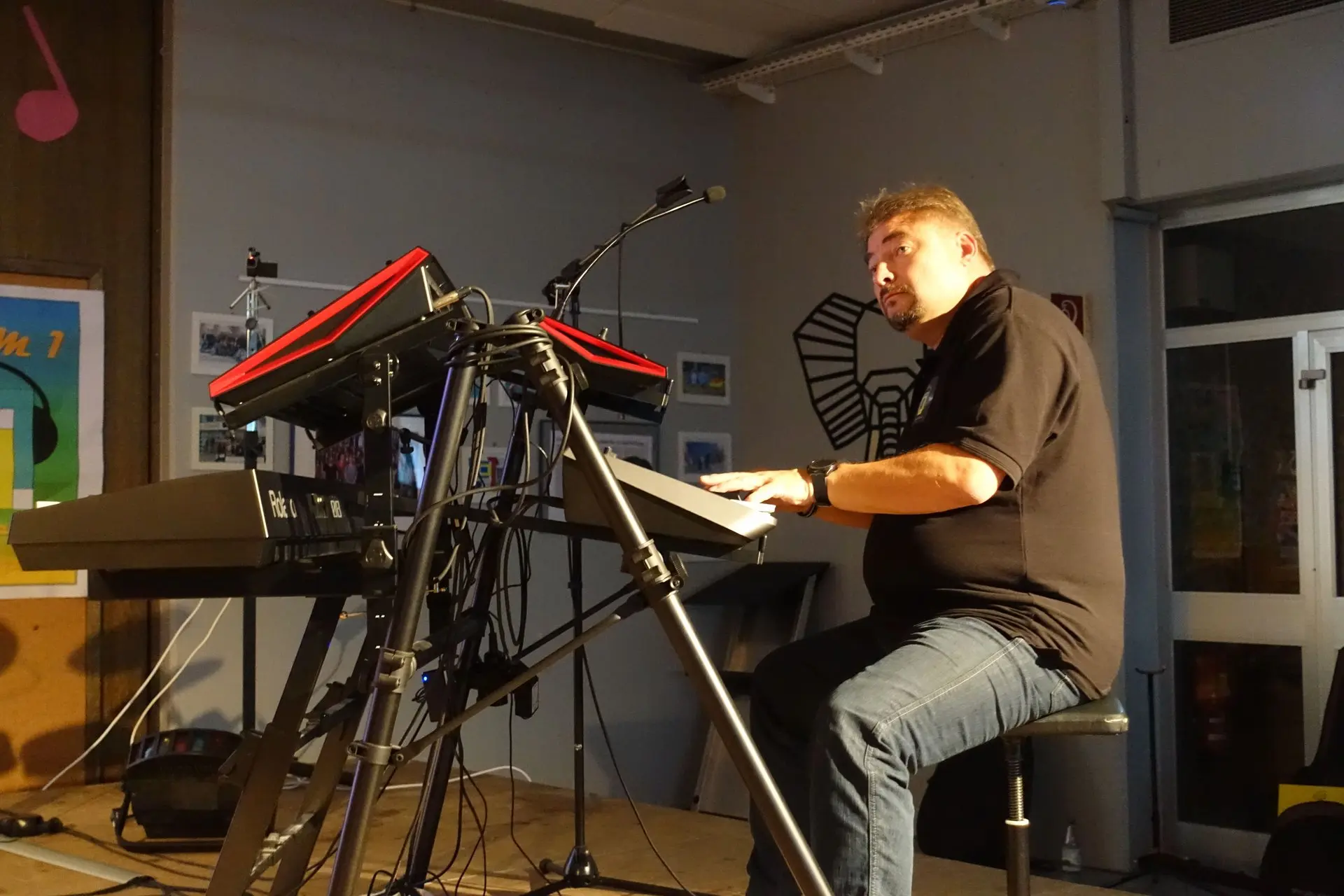 Mann spielt auf der Bühne an Keyboard und E-Piano mit Notenständer beim Konzert