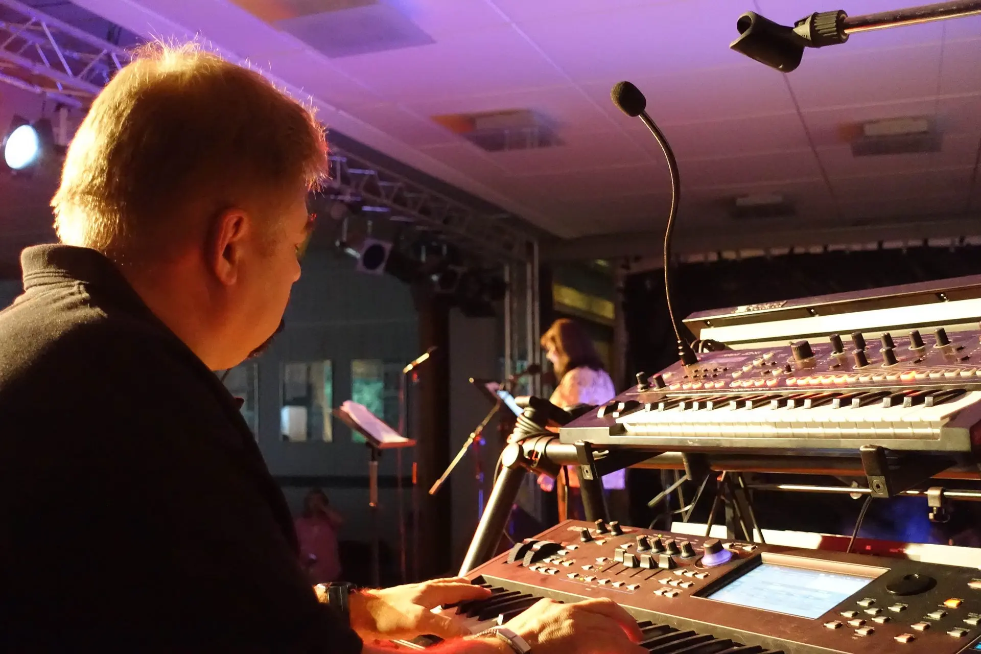 Junge Person bedient bei einem Konzert ein Mischpult mit Keyboard im violetten Licht