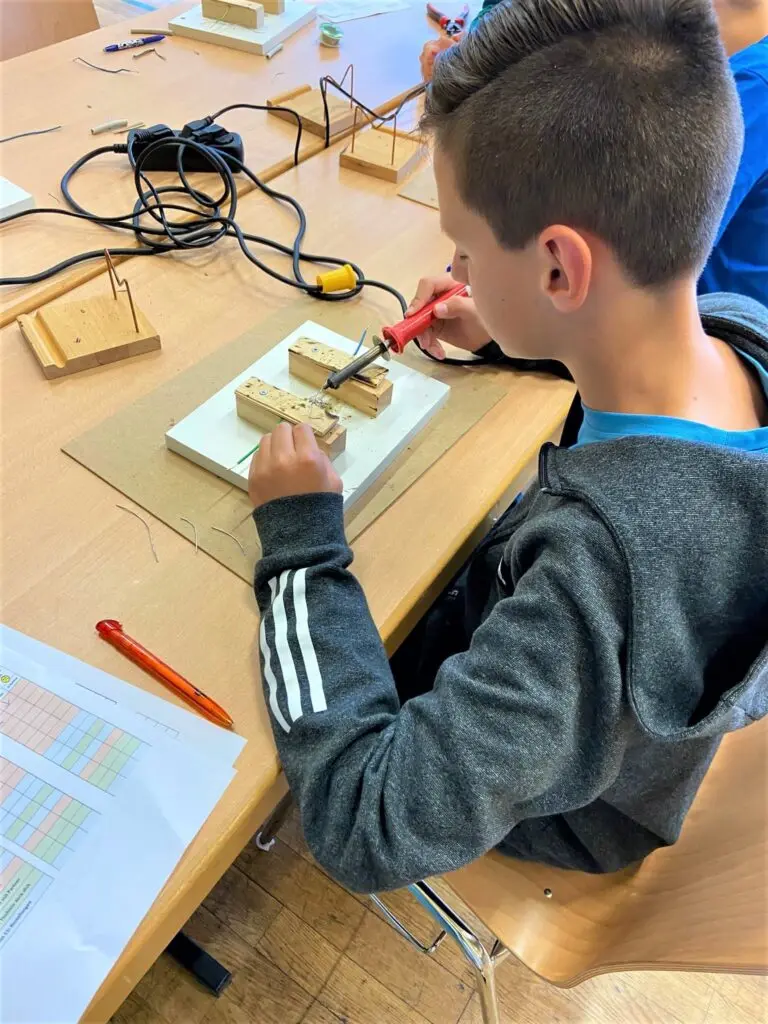 Schüler lötet an einer Werkbank Bauteile auf eine kleine Platine beim Talente-Check