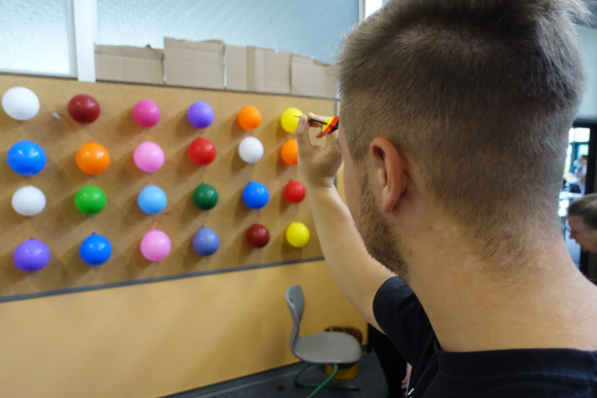 Junge Person spielt an einer Wand mit bunten Kugeln ein Geschicklichkeitsspiel