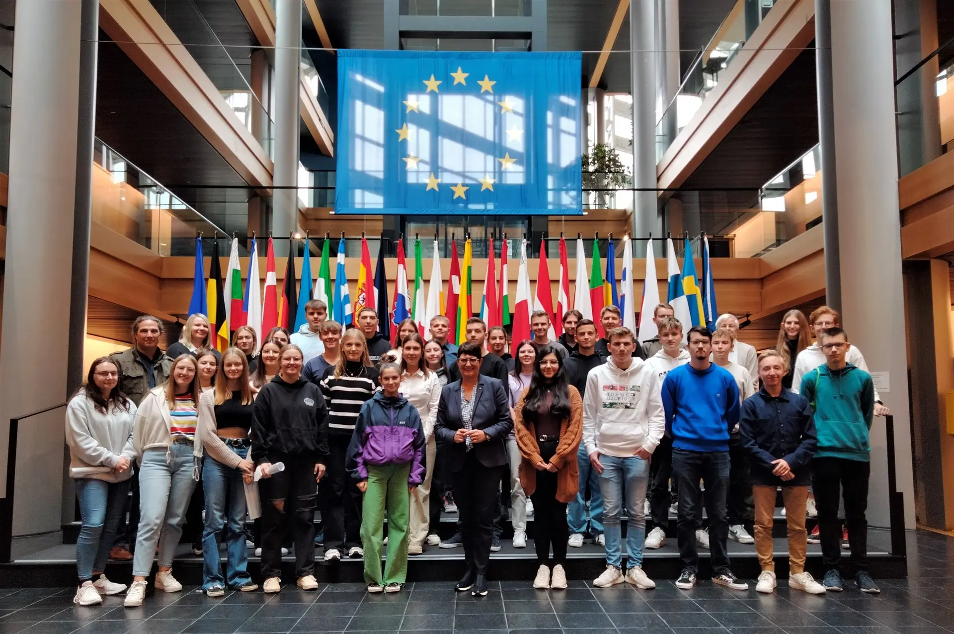Gruppenbild der Schülerinnen und Schüler in einer Halle vor einer Reihe von Europaflaggen