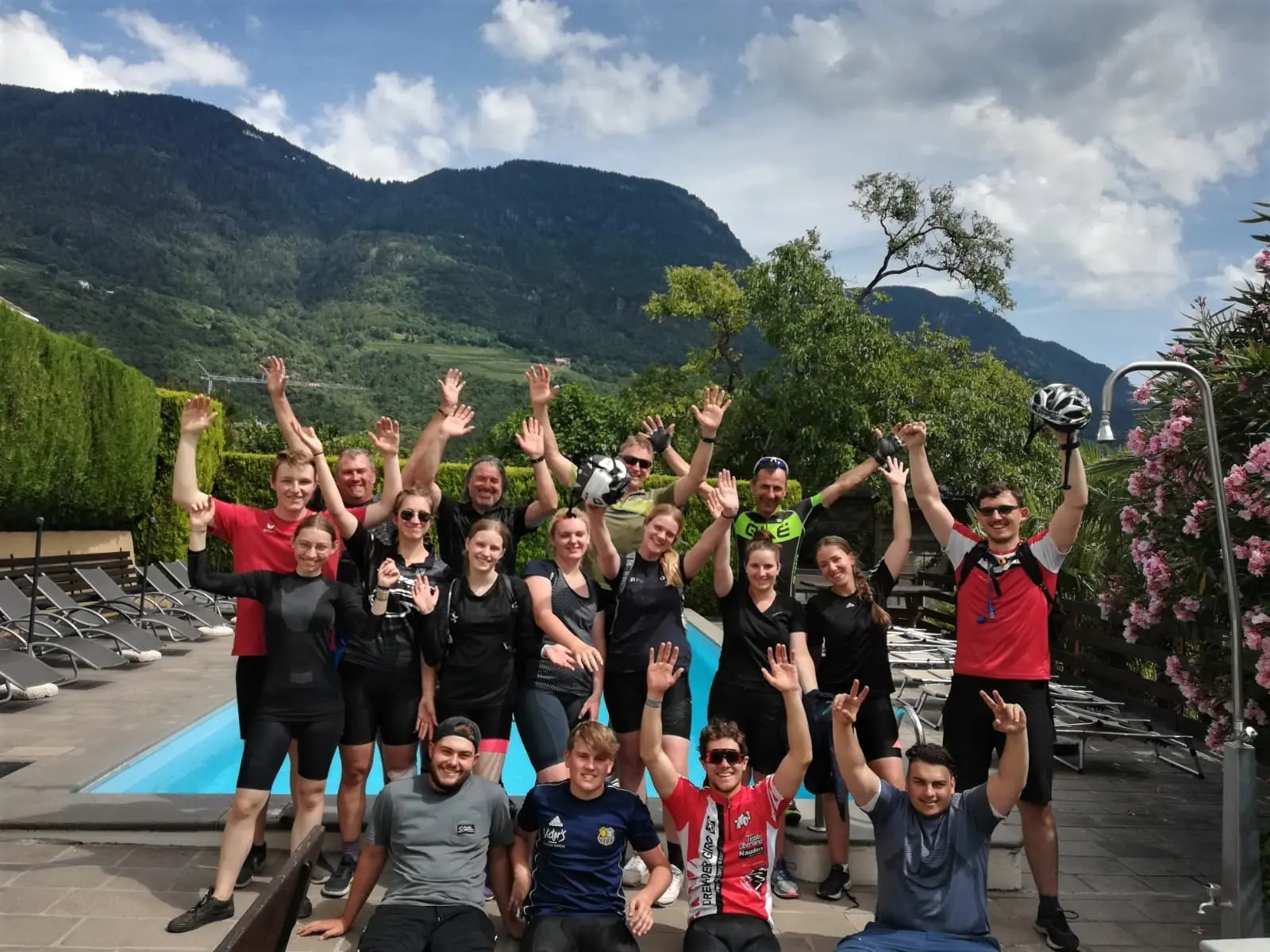 Ausgelassene Gruppe Jugendlicher in Radkleidung vor einer Berglandschaft