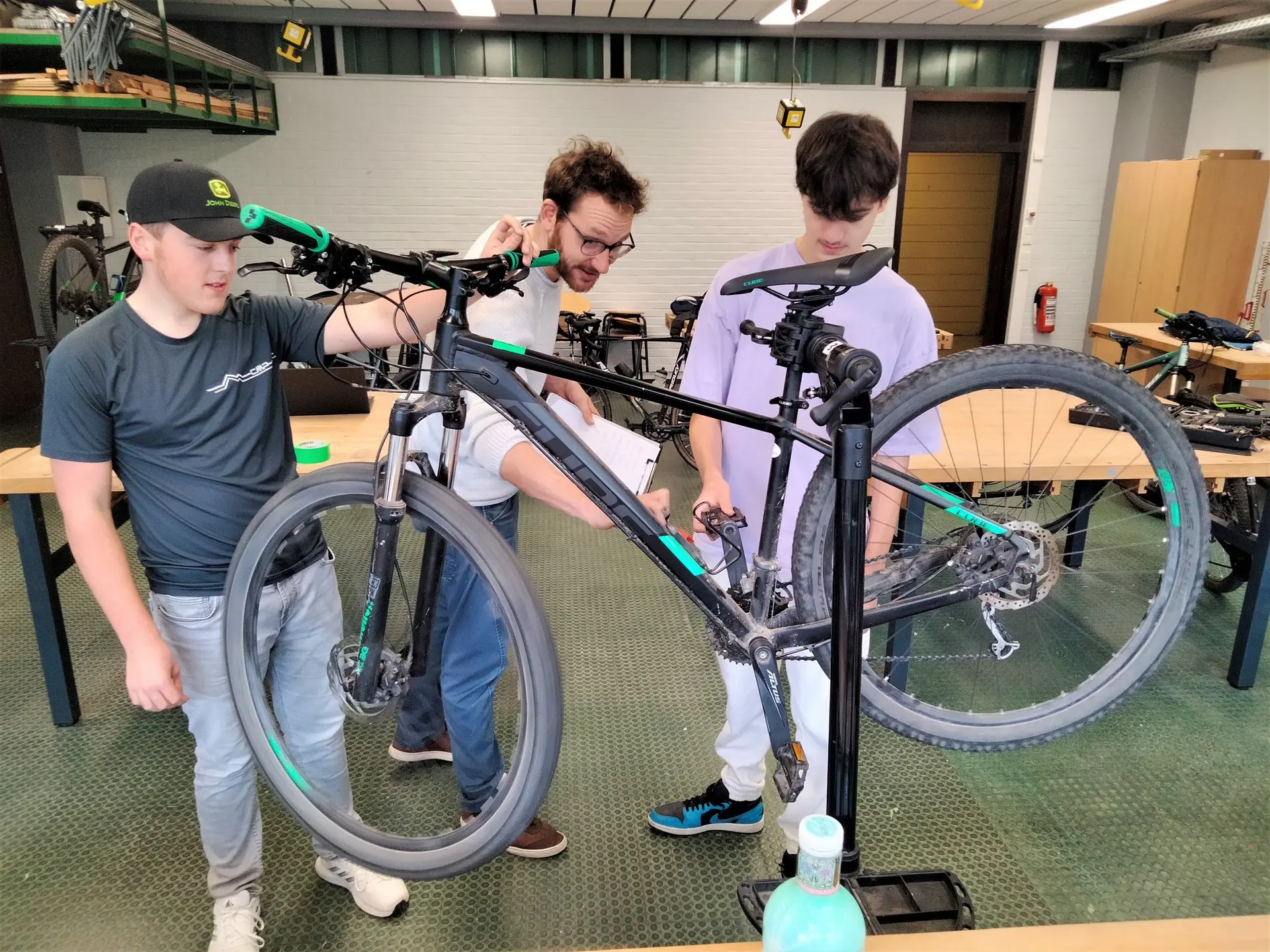 Schüler reparieren in einem Werkraum ein Fahrrad im Montageständer