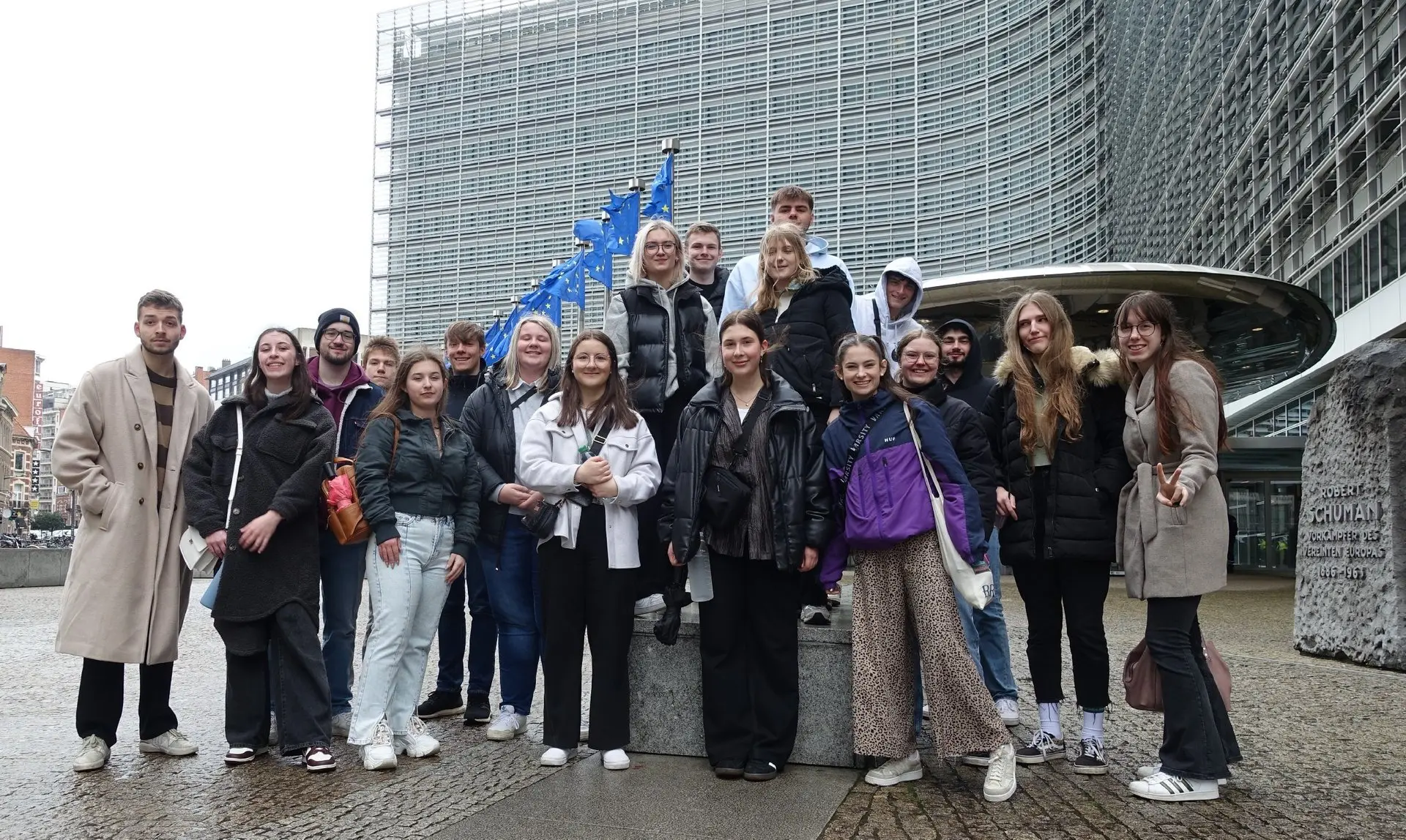 Schülergruppe vor dem großen Glasgebäude des Europäischen Parlaments mit EU-Flagge