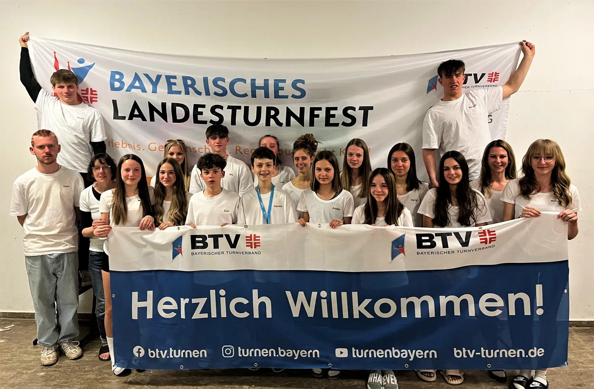 Große Gruppe Jugendlicher hinter einem Banner „Bayerisches Landesturnfest – Herzlich Willkommen!“