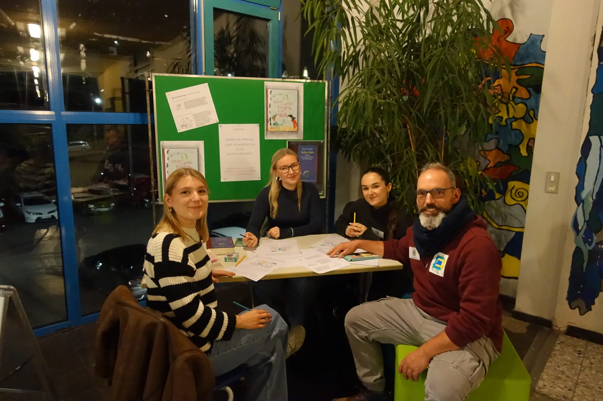 Eltern sitzen mit einem Lehrer an einem Tisch im Foyer und unterhalten sich