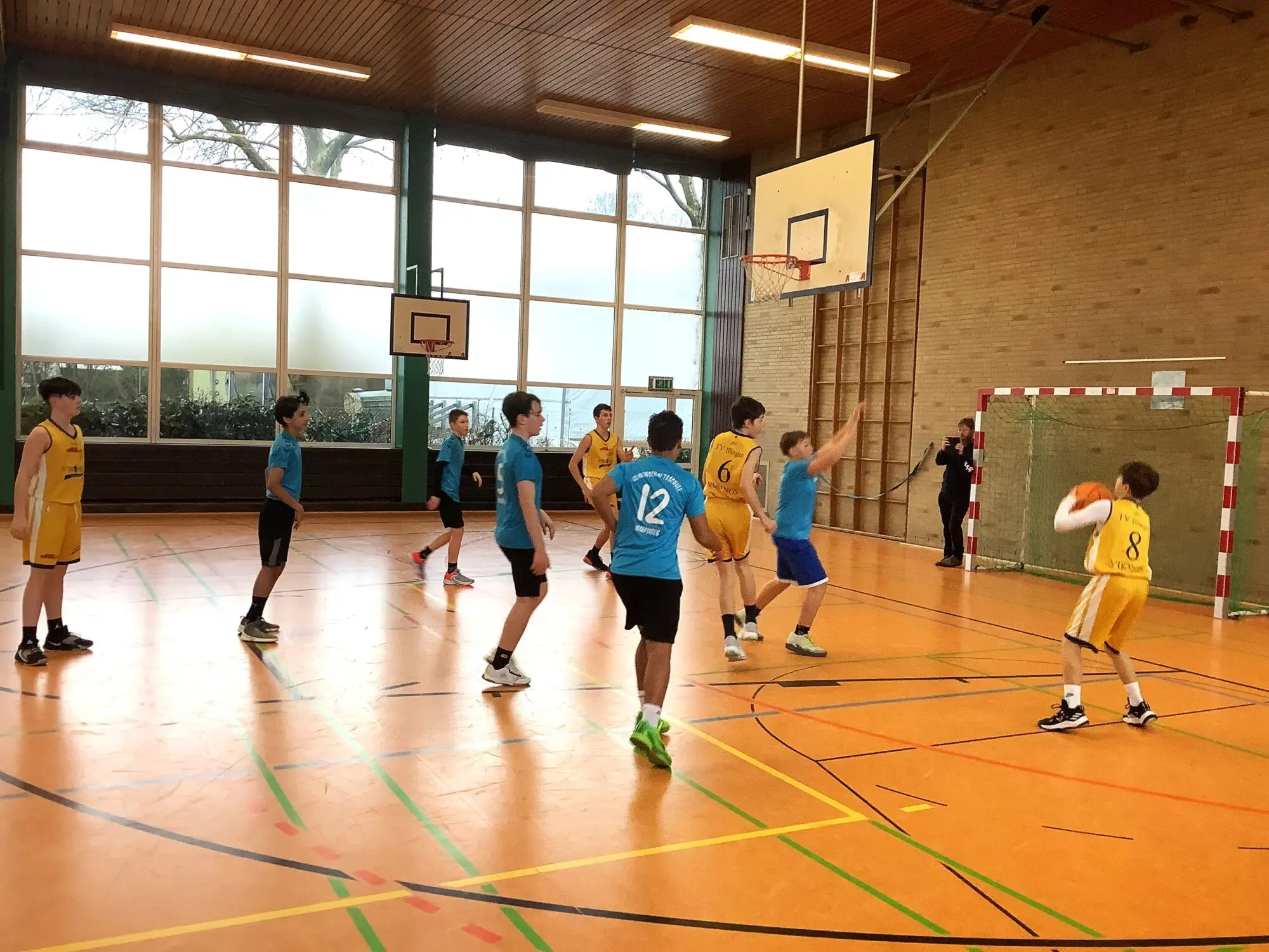 Jugendliche spielen Fußball in einer Sporthalle mit Basketballkorb