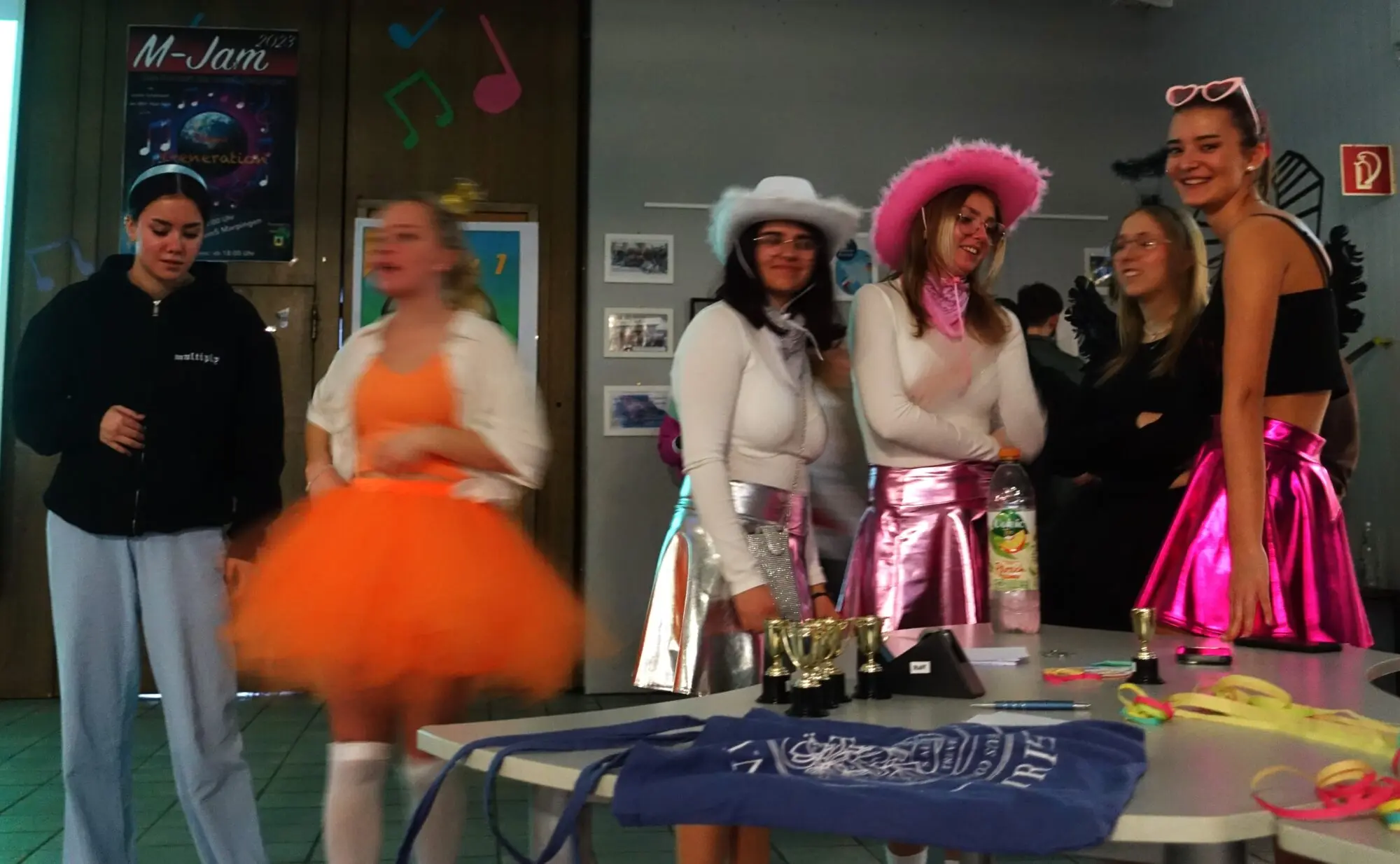 Kostümierte Jugendliche mit Cowboyhüten und Tutus vor einem Tisch auf der Feier