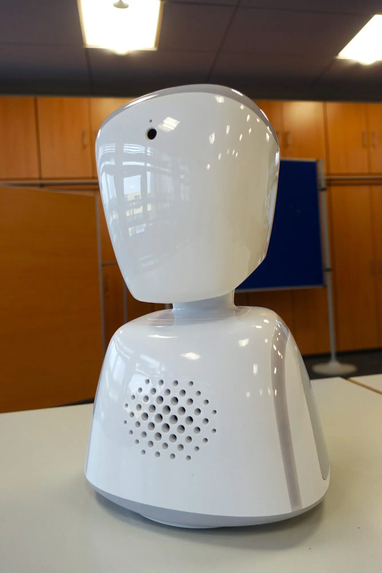 Kleiner weißer Telepräsenz-Roboter mit Kopf und Kamera steht auf einem Tisch