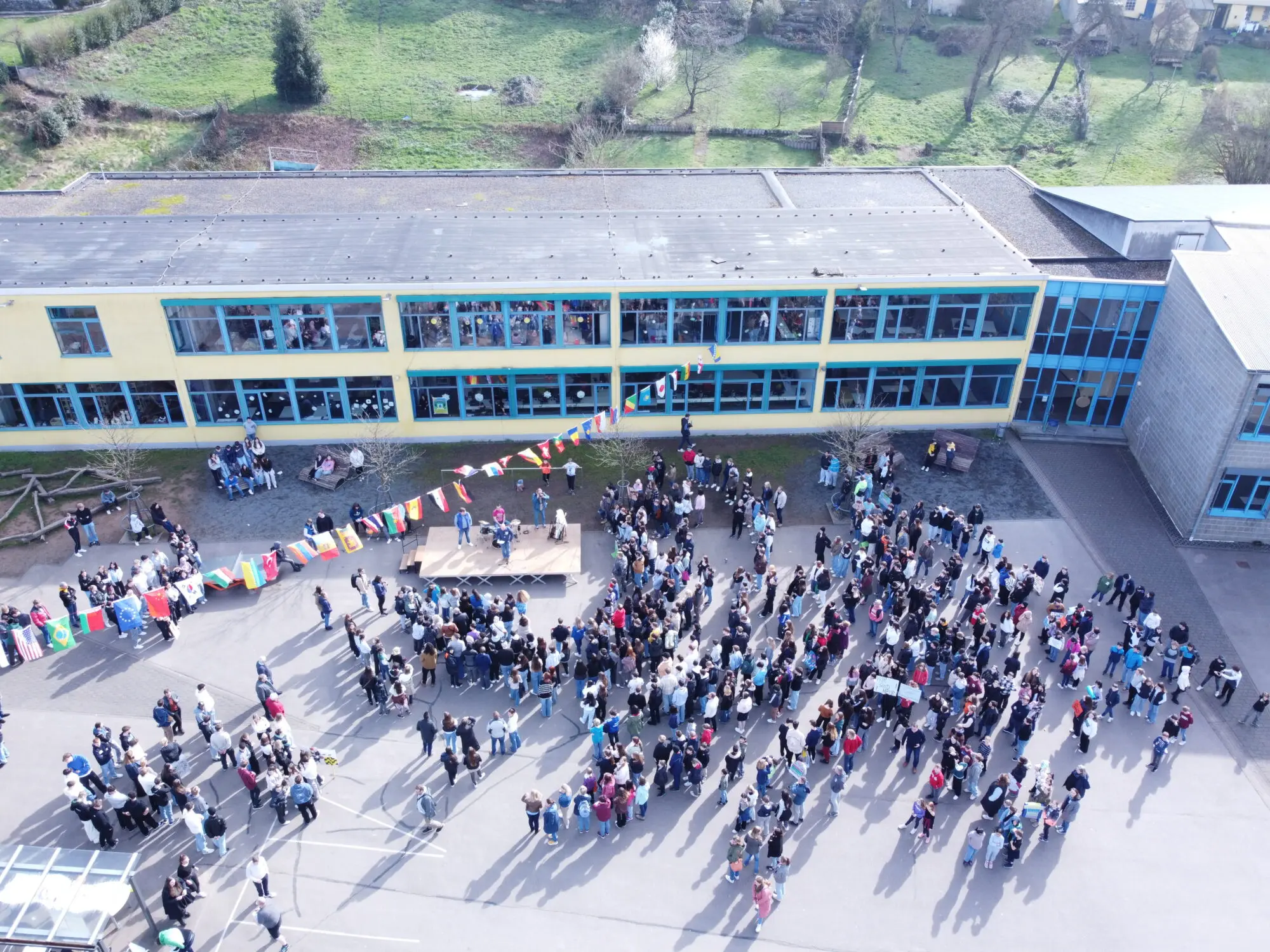 Drohnenaufnahme der Schulgemeinschaft, die sich auf dem Schulhof vor dem Gebäude versammelt