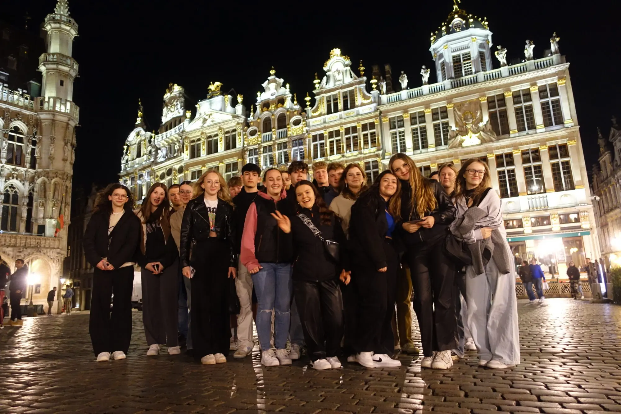 Schülergruppe posiert abends vor den beleuchteten Gildehäusern am Brüsseler Grand-Place