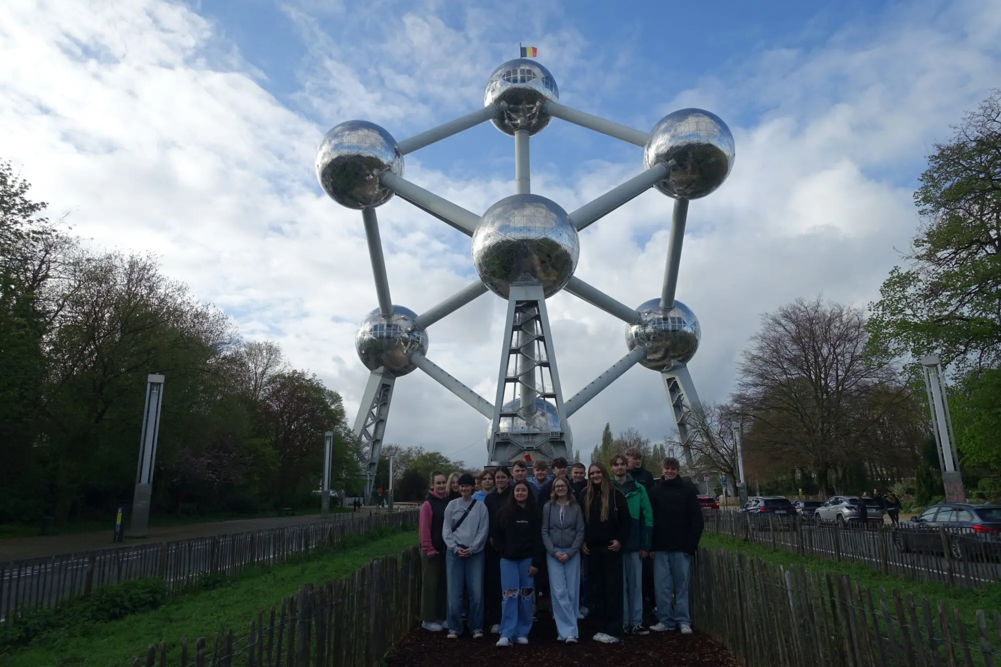 Schülergruppe steht klein vor dem Atomium in Brüssel unter bewölktem Himmel