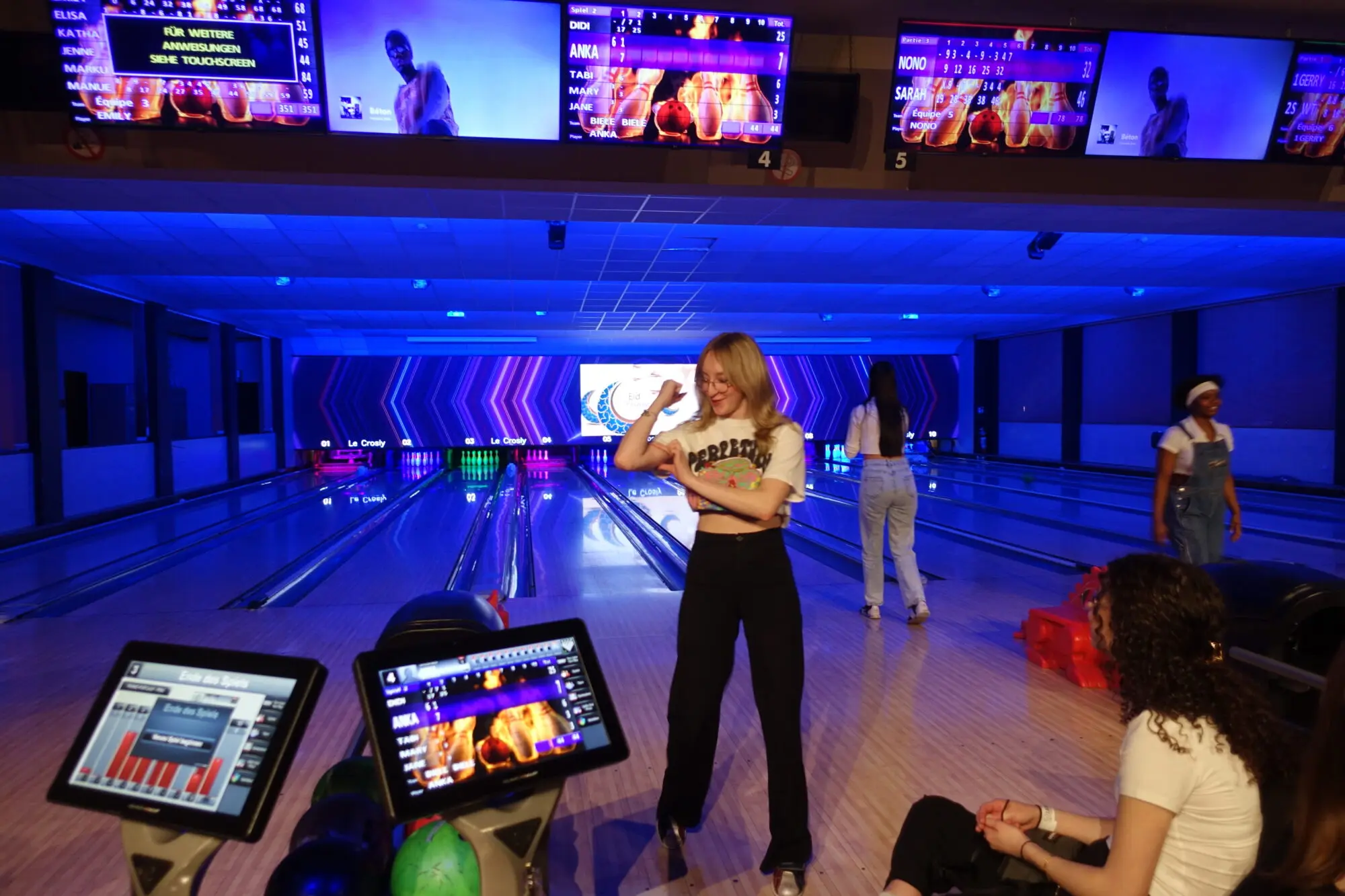 Schülerin wirft eine Bowlingkugel auf einer neonbeleuchteten Bowlingbahn