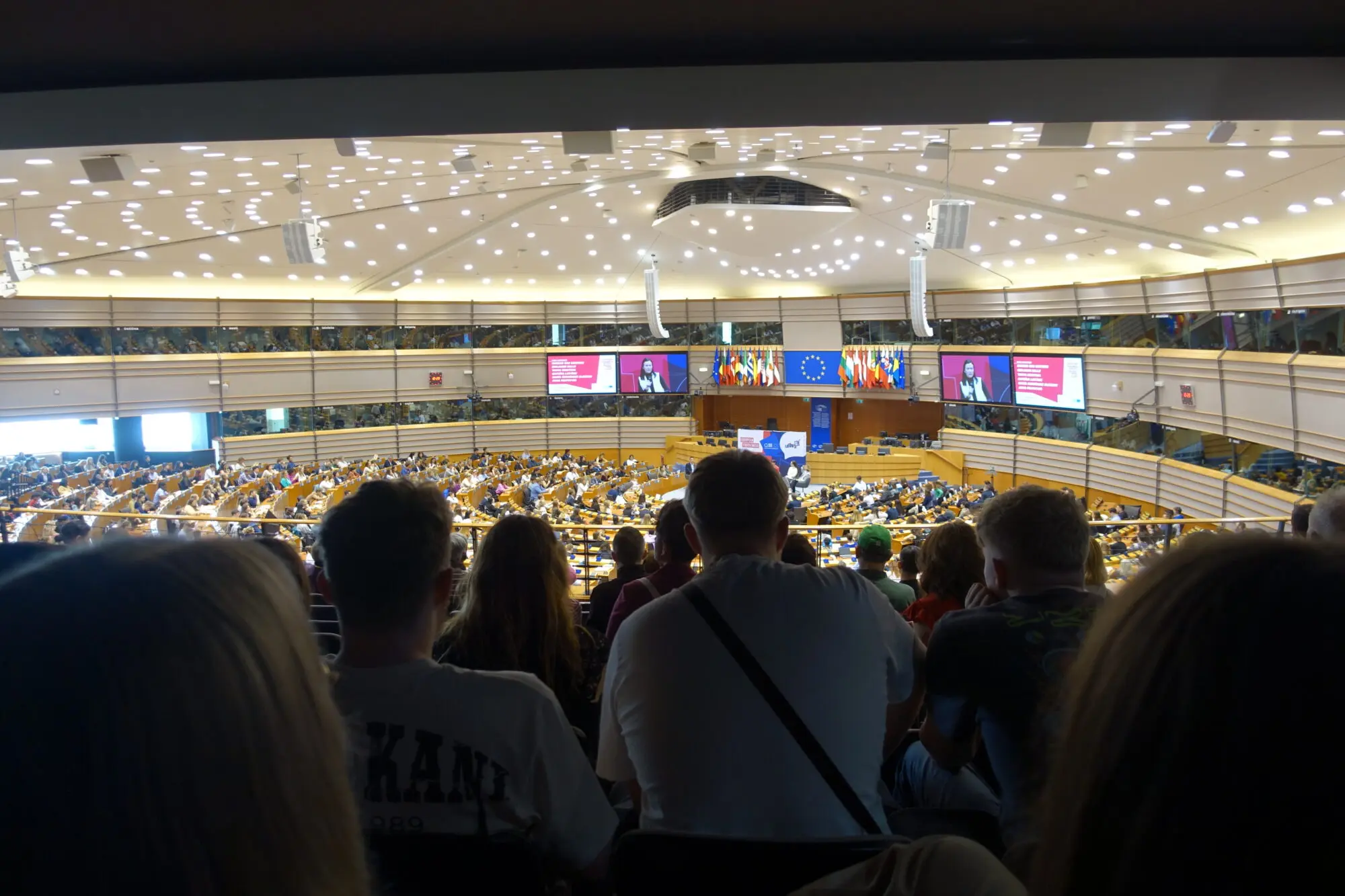 Schülerinnen und Schüler sitzen auf der Besuchertribüne und blicken in einen großen Plenarsaal
