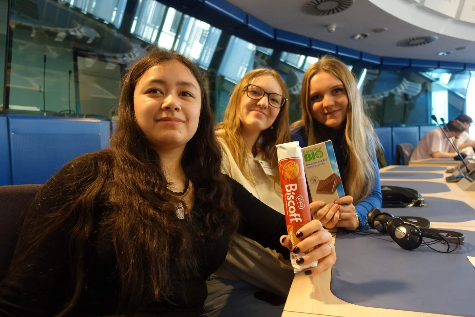 Drei Schülerinnen machen ein Selfie im Konferenzsaal, eine hält einen Info-Flyer