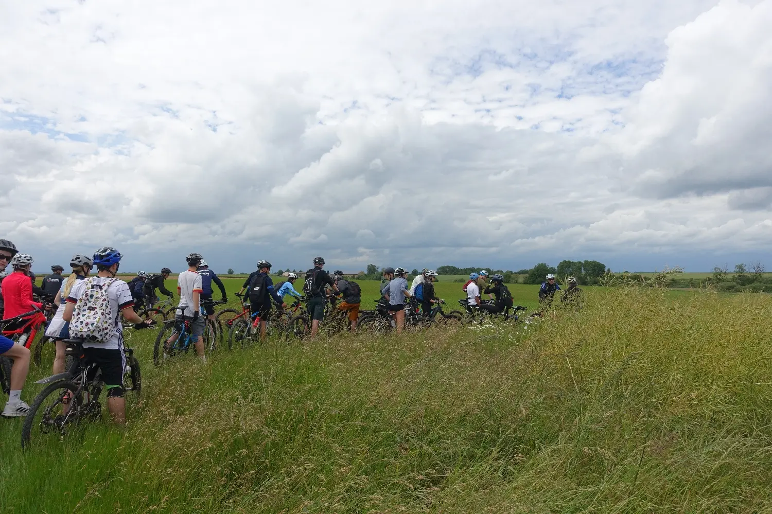 Radfahrende Gruppe macht mit ihren Rädern Pause am Rand einer grünen Wiese