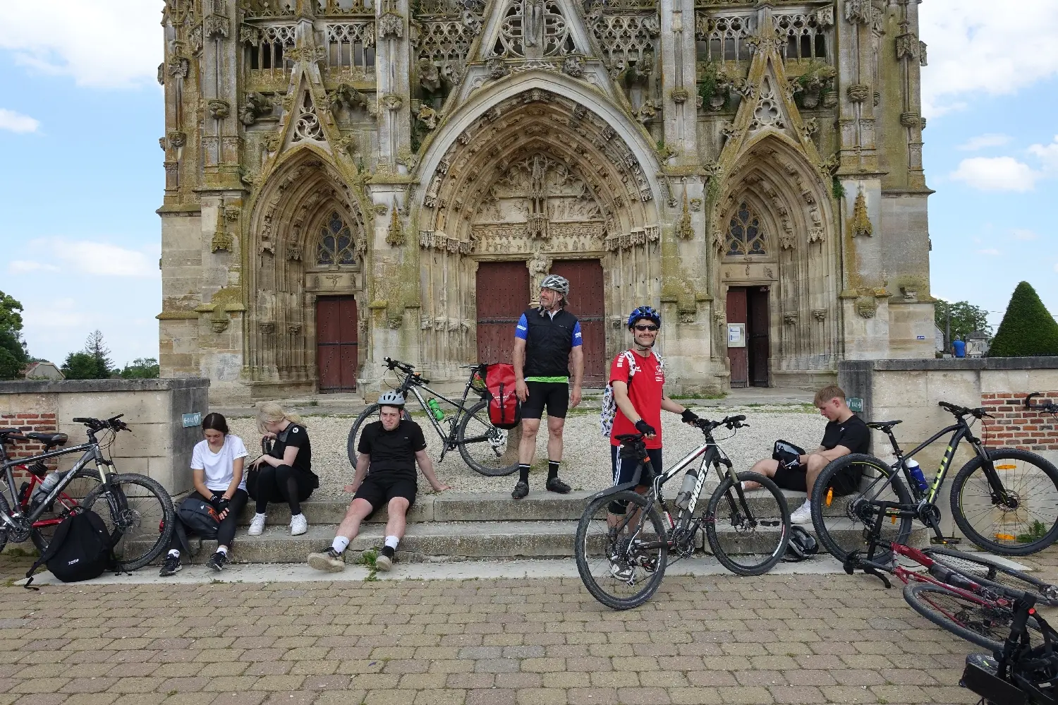 Radfahrende mit Fahrrädern vor der Fassade einer gotischen Kathedrale