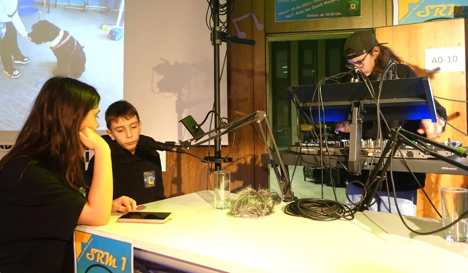 Schülerin und Kind an einem Tisch in einem Studio mit Mikrofon und Technik