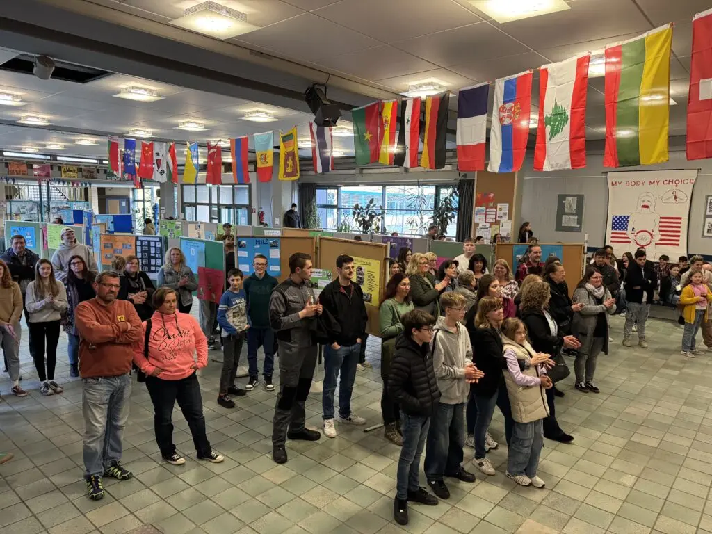 Viele Besucher in der mit Länderfahnen geschmückten Pausenhalle der Schule