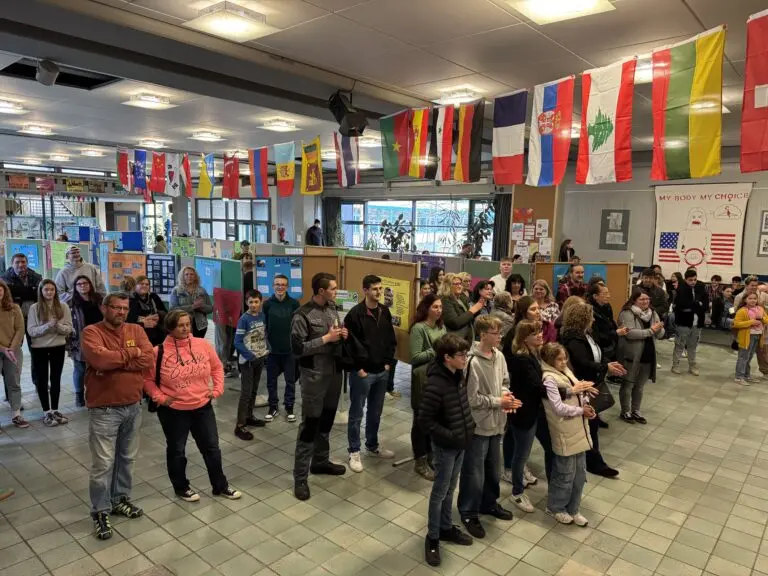 Viele Besucher in der mit Länderfahnen geschmückten Pausenhalle der Schule