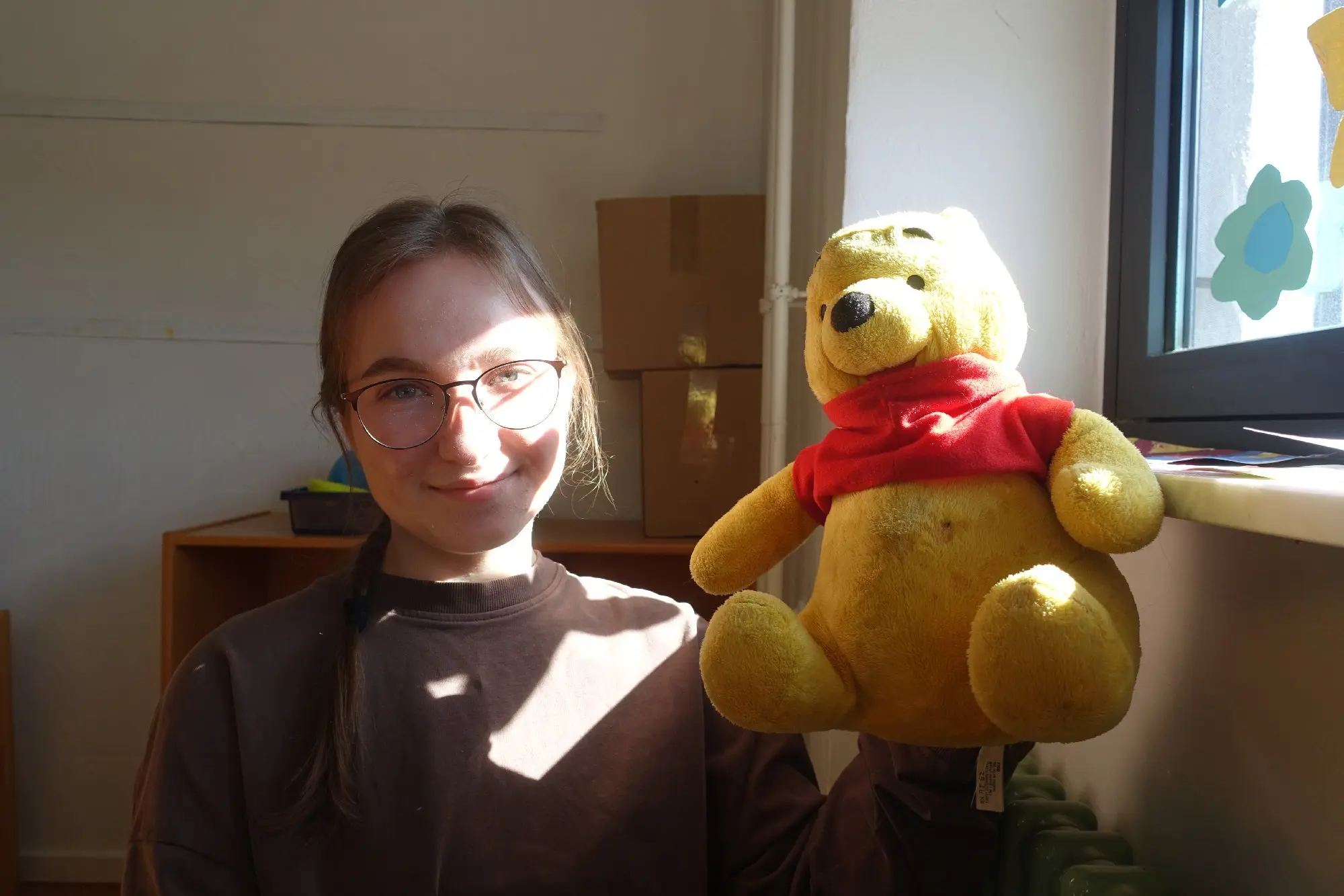 Junge Frau lächelt neben einem großen Winnie-Puuh-Plüschtier