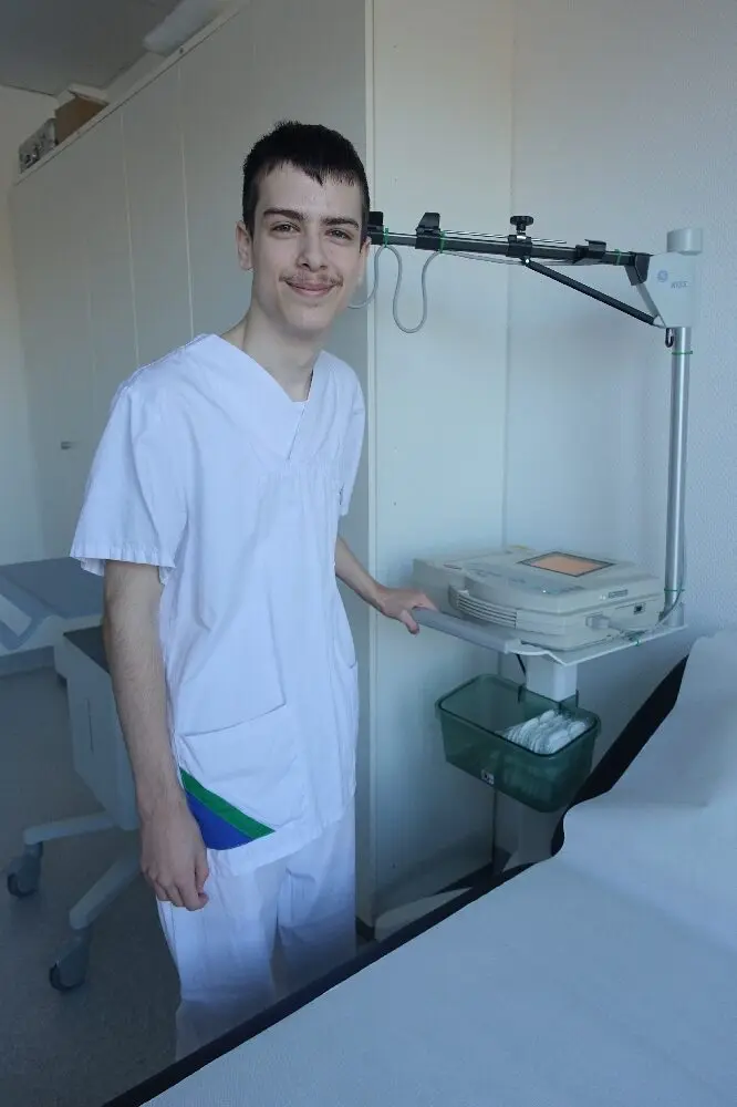 Junger Mann in weißer Kleidung steht in einem Krankenhauszimmer