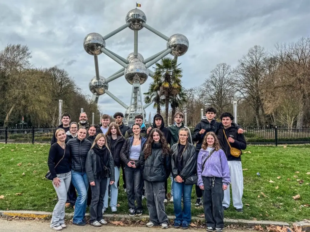 Schülergruppe steht auf einer Wiese vor dem Atomium in Brüssel
