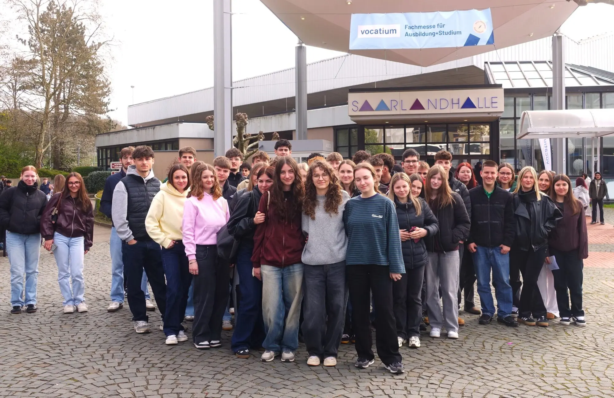 Große Schülergruppe steht für ein Gruppenfoto vor einem Gebäude