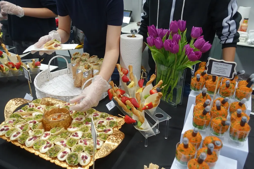 Buffet mit Häppchen, Spießen, Gebäck und Tulpen, Helfer mit Handschuhen