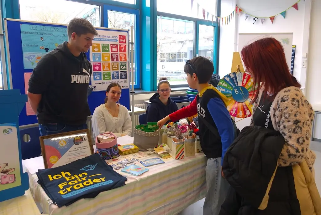 Infostand mit Plakaten und Tisch, Jugendliche und Erwachsene im Gespräch