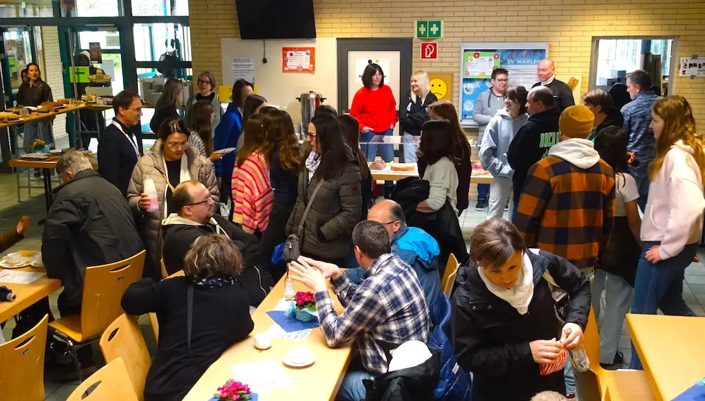 Voller Raum mit Besucherinnen und Besuchern an Tischen in der Mensa