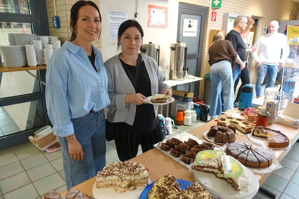 Zwei Frauen stehen an einem Tisch mit Kuchen und Gebäck beim Verkauf