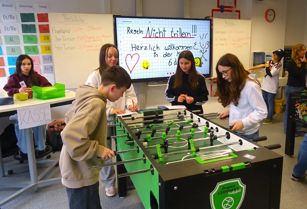 Schülerinnen und Schüler spielen Tischkicker in einem Klassenraum