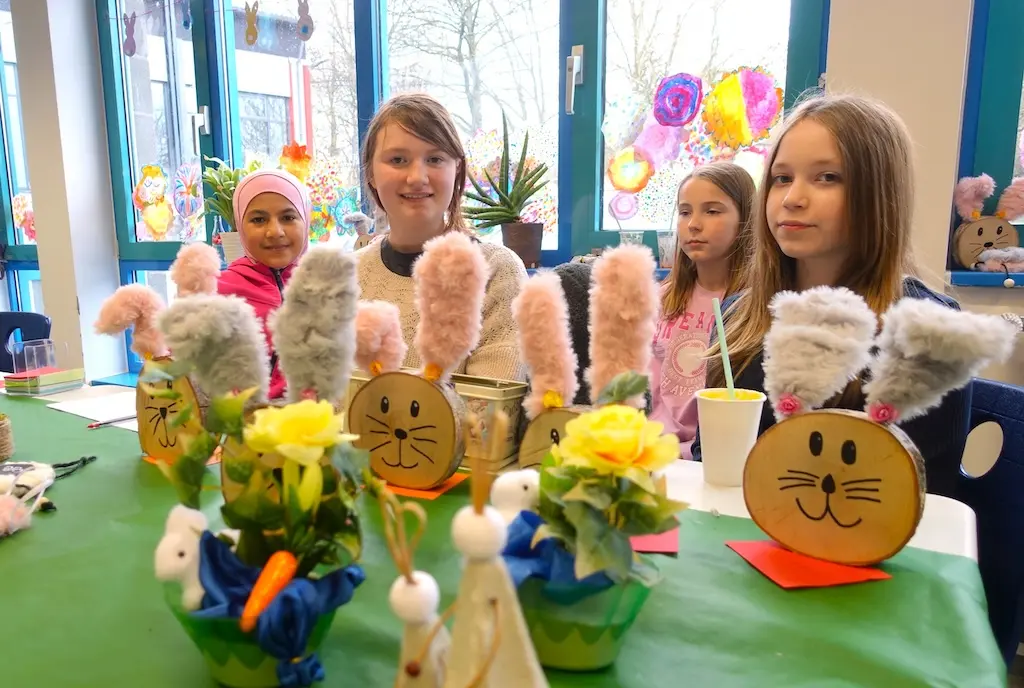 Verkaufstisch mit gebastelten Osterfiguren und Blumen, dahinter Schülerinnen
