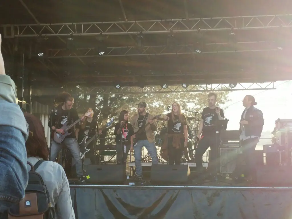 Band spielt auf einer großen Freiluftbühne mit Traversen, davor Publikum