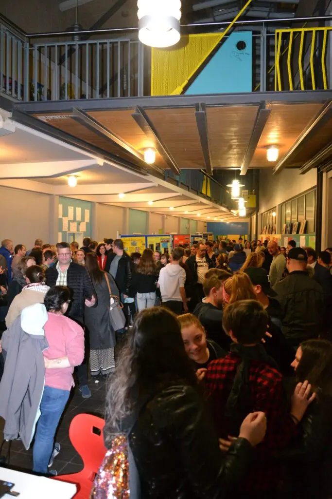 Viele Menschen bei einer Veranstaltung in der Aula, darüber eine Galerie mit Geländer