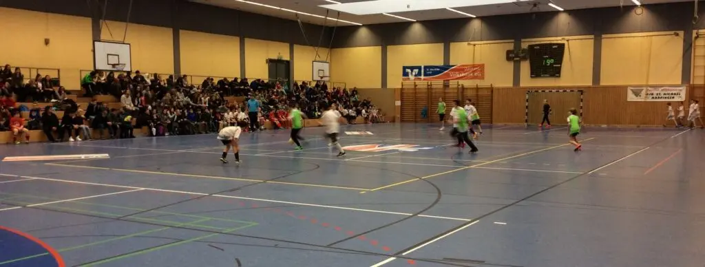 Blick über ein Hallenfußballspiel in einer großen Sporthalle mit vollen Zuschauerrängen