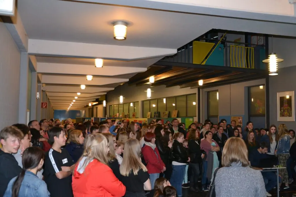 Viele Schülerinnen und Schüler stehen dicht gedrängt in der Aula unter den Galerien