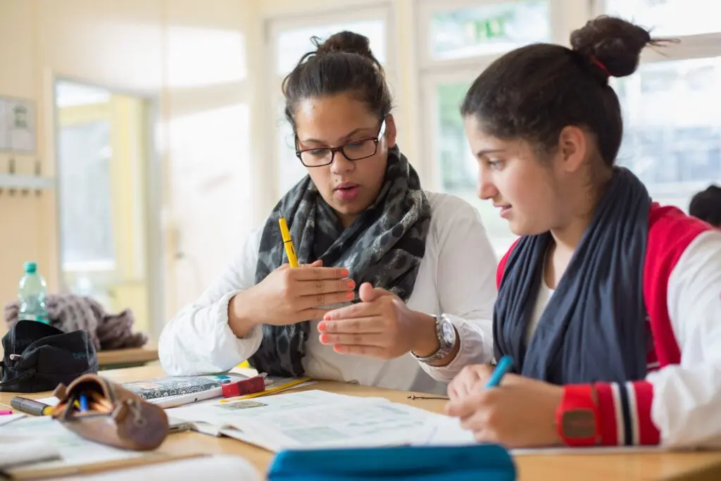 Zwei Schülerinnen arbeiten bei der Lernförderung gemeinsam mit Stift und Heft an einem Tisch